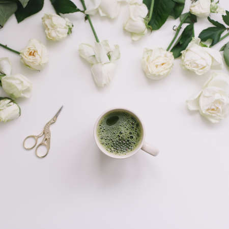 A cup of green tea with white roses on white background view from above. Flatlay, top view, copy spaceの写真素材