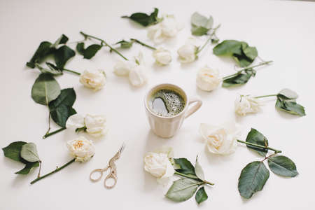 Beautiful composition with cup of matcha tea and flowers on white background. Flatlay, top viewの写真素材