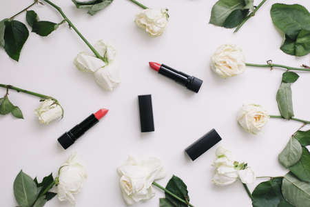 Composition with white roses and red lipsticks. Flat lay on white table, top viewの写真素材