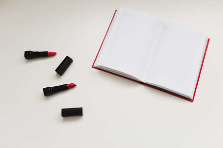 open notebook with cosmetics, accessories on white background. Minimal home workspace desk table....