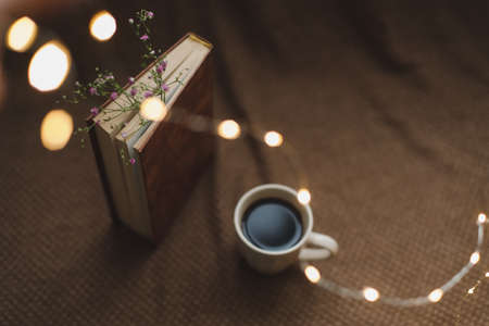 A book with flowers and cup of coffee on dark background top viewの写真素材