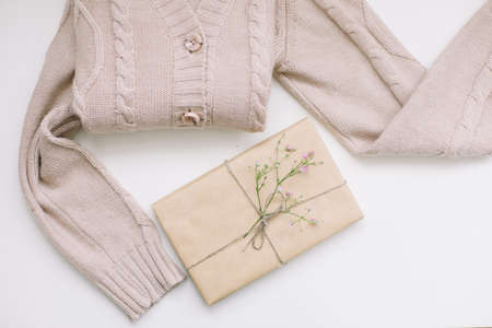 beige knitted sweater and a gift in craft paper, top viewの写真素材