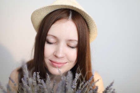 portait of a beautiful young woman wearing summer hat and holding lavender flowersの写真素材
