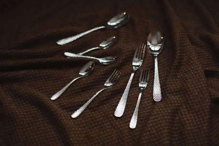 silver stainless cutlery on a dark fabric backgroundの写真素材
