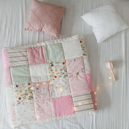 Cozy baby cot with a patchwork blanket. Baby bedding and textile for nurseryの写真素材