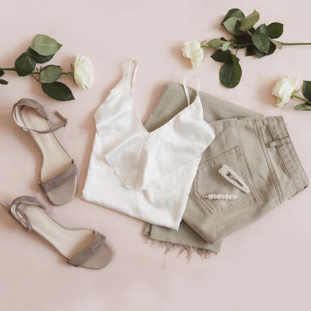 Jeans, sandals and bouquet of flowers on beige background. Top view of female casual spring summer outfit. Trendy stylish women clothes. Flat layの写真素材