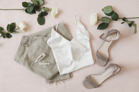 Jeans, sandals and bouquet of flowers on beige background. Top view of female casual spring summer outfit. Trendy stylish women clothes. Flat layの写真素材