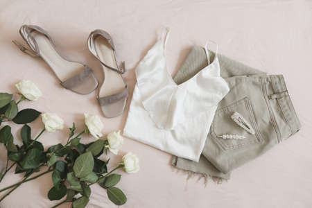 Jeans, sandals and bouquet of flowers on beige background. Top view of female casual spring summer outfit. Trendy stylish women clothes. Flat layの写真素材
