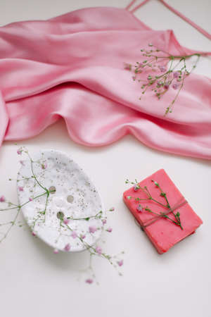 Spa composition with pink soap bar with ceramic soap dish, silk babric and flowersの写真素材