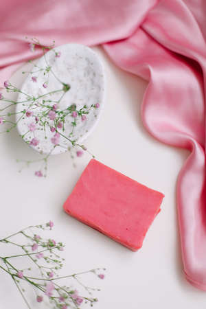 Spa composition with pink soap bar with ceramic soap dish, silk babric and flowersの写真素材