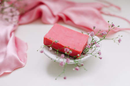 Spa composition with pink soap bar with ceramic soap dish, silk babric and flowersの写真素材