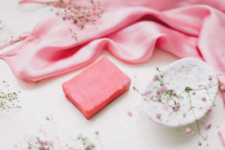 Spa composition with pink soap bar with ceramic soap dish, silk babric and flowersの写真素材