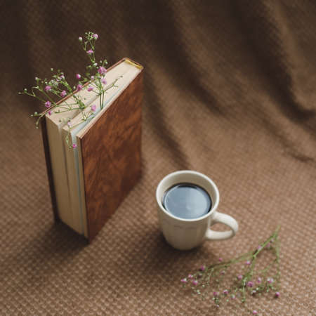A book with flowers and cup of coffee on dark background top viewの写真素材