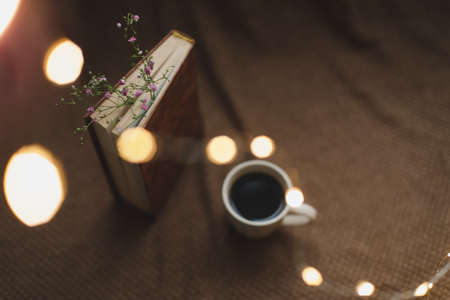 A book with flowers and cup of coffee on dark background top viewの写真素材