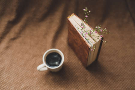 A book with flowers and cup of coffee on dark background top viewの写真素材