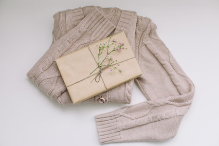 beige knitted sweater with a gift in craft paper top view with copyspaceの写真素材
