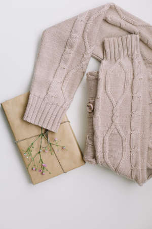 beige knitted sweater with a gift in craft paper top view with copyspaceの写真素材