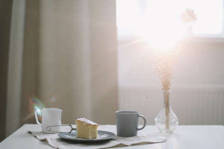 Morning breakfast with a piece of fresh homemade cake, pitcher and cup of coffee on a tableの写真素材