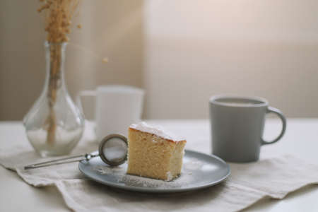 Morning breakfast with a piece of fresh homemade cake, pitcher and cup of coffee on a tableの写真素材