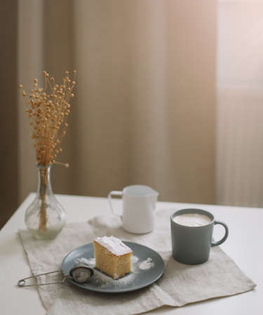 Morning breakfast with a piece of fresh homemade cake, pitcher and cup of coffee on a table