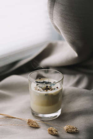 aromatic scented candle with smoke and dried flowers on beige textile backgroundの写真素材
