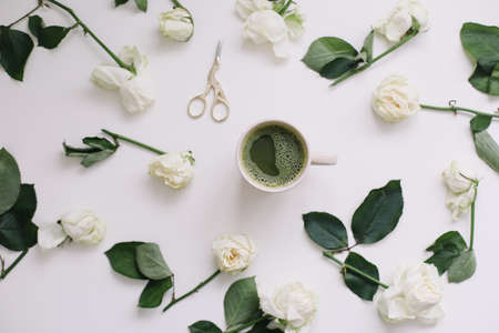 A cup of green tea with white roses on white background view from above. Flatlay, top view, copy space.の写真素材