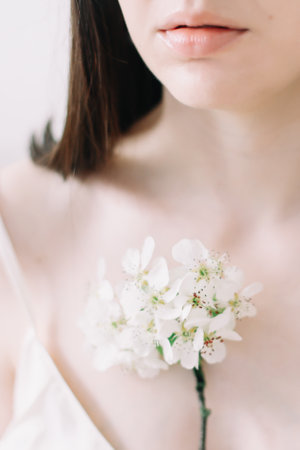 Young beautiful woman with flowers on white background. Tender pure portrait. Face skincare and health wellness, Natural makeup.の写真素材