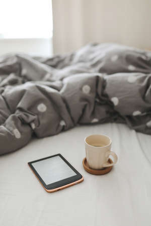 E-book and a cup of coffee in bed on the sheets. Good morning. Breakfast in bedの写真素材