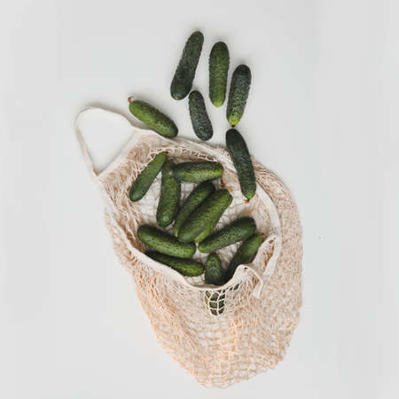 Green fresh cucumbers in a reusable string bag isolated on white background. Concept zero waste. Top view.の写真素材