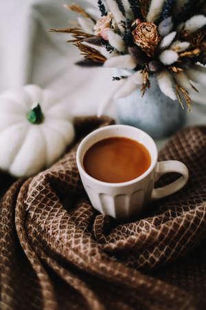Autumn still life with a coffee cup with flowers and pumpkins on a cozy plaid in bed. Stylish autumn flat lay.の写真素材