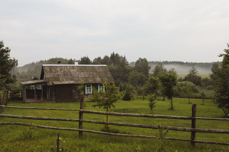 a wooden farmhouse in a country scene on a cloudy dayの写真素材