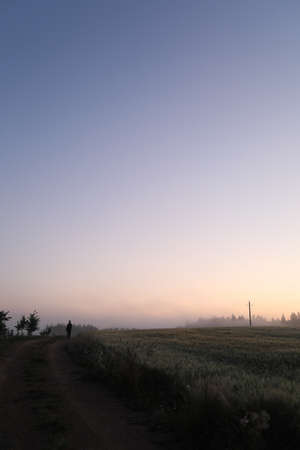 silhouette of a man walking in a scenic countryside landscape at sunrise