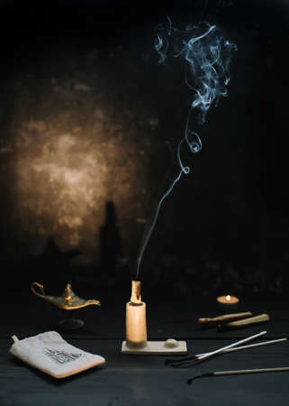 Palo Santo stick on fire with smoke in a beautiful candlestick. Healing, meditation, relaxation, purifying concept. Palo santo wood, Aromatic sticks on dark background. Cozy evening at home.の写真素材