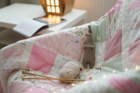 Cozy homely background with wool yarn and knitting needles on an armchair with a blanket.