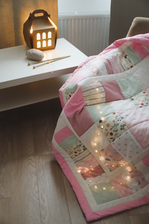 Cozy room with an armchair with a blanket, wool yarn and knitting needles on a table by the window