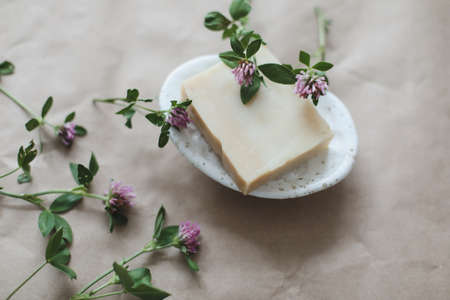 Handmade natural spa organic soap with flowers on ceramic soap dish on craft paper background top view with copyspaceの写真素材