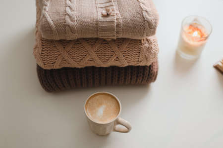 cozy comfortable hygge home atmosphere and still life with a cup, candle and sweaters