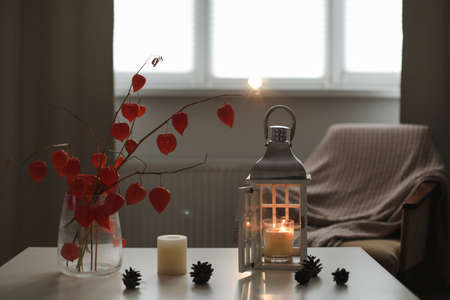 cozy autumn still life, candles, flowers, twigs of orange physalis in a vase and details of home...