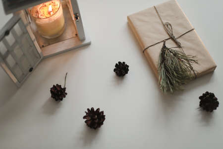 winter flatlay with a christmas and new year gift in craft paper, candle, pine twig and cones top viewの写真素材
