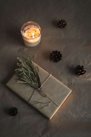 winter flatlay with a christmas and new year gift in craft paper, candle, pine twig and cones top viewの写真素材