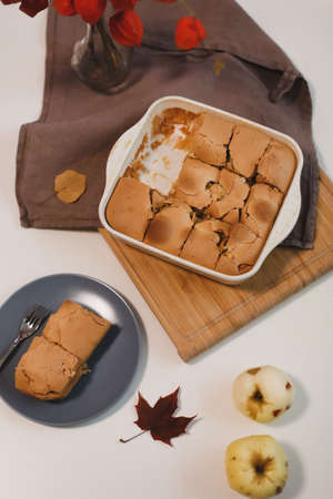 Cozy home breakfast with apple pie, bouquet of red flowers on a table in a sunny roomの写真素材