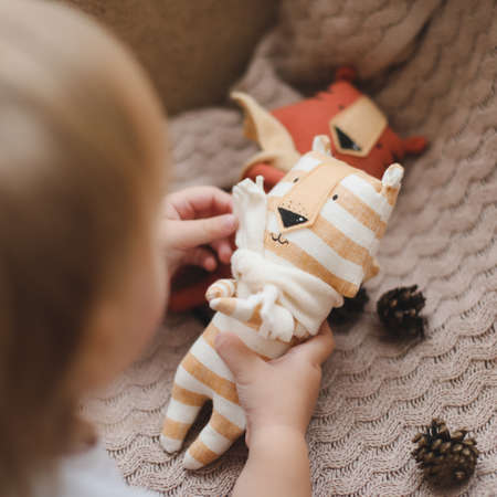 Little baby girl playing with funny small tiger toy, symbol of new 2022 in a sunny nurseryの写真素材