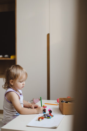 a little funny girl draws with pencils in the nursery at homeの写真素材
