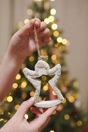 Decorating Christmas tree, holding Christmas toy in a hand. Holiday, Christmas and New Year family celebration conceptの写真素材