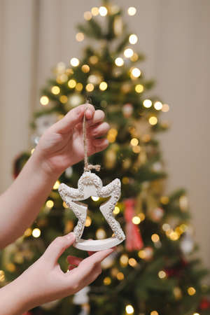 Decorating Christmas tree, holding Christmas toy in a hand. Holiday, Christmas and New Year family celebration conceptの写真素材