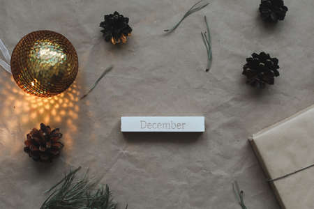 Word December on calendar by background with spruce branches and a glowing garland. Christmas,...