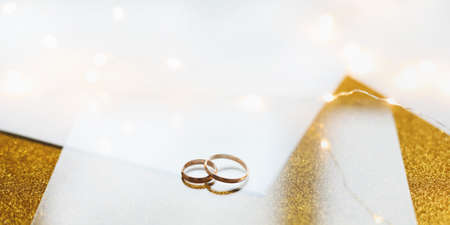 Two golden wedding rings on a golden background. Wedding invitation. valentine gift, sale shopping banner template, copy spaceの写真素材