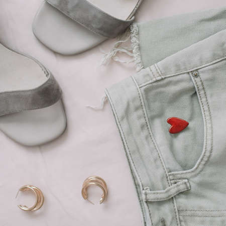 Jeans, sandals and red lipstick on beige background. Overhead view of womans casual spring summer outfit. Trendy stylish women clothes. Flat lay, top viewの写真素材