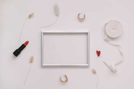 minimal fashion mockup with empty photo frame and red lipstick and womens accessories on white backgroundの写真素材