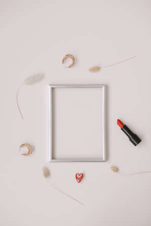 minimal fashion mockup with empty photo frame and red lipstick and womens accessories on white backgroundの写真素材
